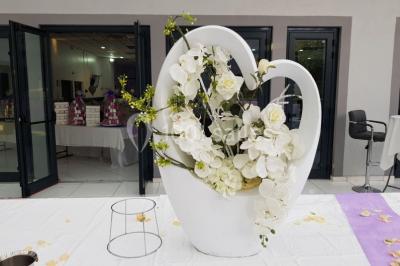 Lettres rouges formant le mot ’LOVE’ sur un tapis rouge, entourées de petites décorations blanches, en extérieur.