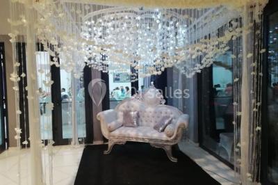 Lettres rouges formant le mot ’LOVE’ sur un tapis rouge, entourées de petites décorations blanches, en extérieur.