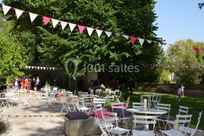Chambre avec lit ancien en bois sculpté, murs rouges, tables de chevet assorties et miroir ovale.