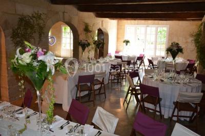 Chambre avec lit ancien en bois sculpté, murs rouges, tables de chevet assorties et miroir ovale.