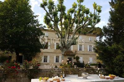 Chambre avec lit ancien en bois sculpté, murs rouges, tables de chevet assorties et miroir ovale.