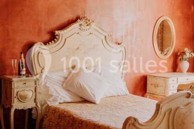 Chambre avec lit ancien en bois sculpté, murs rouges, tables de chevet assorties et miroir ovale.