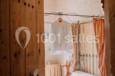 Chambre avec lit ancien en bois sculpté, murs rouges, tables de chevet assorties et miroir ovale.