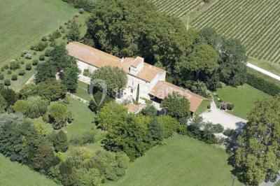 Chambre avec lit ancien en bois sculpté, murs rouges, tables de chevet assorties et miroir ovale.