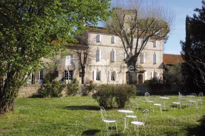 Chambre avec lit ancien en bois sculpté, murs rouges, tables de chevet assorties et miroir ovale.
