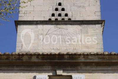 Chambre avec lit ancien en bois sculpté, murs rouges, tables de chevet assorties et miroir ovale.