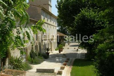 Chambre avec lit ancien en bois sculpté, murs rouges, tables de chevet assorties et miroir ovale.
