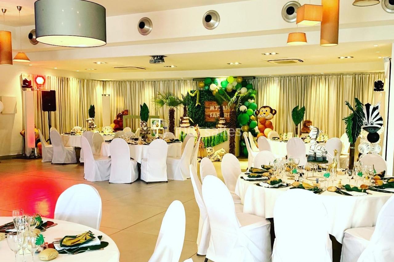 Salle de réception décorée sur le thème de la jungle avec des tables dressées et des éléments décoratifs exotiques.