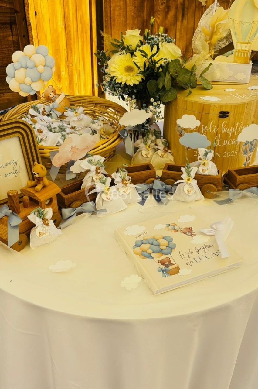 Table décorée pour une fête avec fleurs, ballons, cadeaux et éléments sur le thème des nuages et montgolfières.
