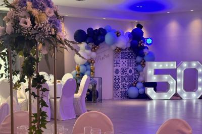 Table décorée pour une fête avec des donuts glacés bleus, des cubes décoratifs et des desserts variés sur des supports en…