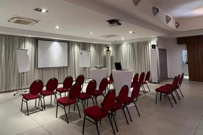 Salle aménagée avec des rangées de chaises rouges alignées, prête pour un événement ou une réunion.