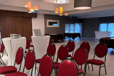 Salle aménagée avec des rangées de chaises rouges alignées, prête pour un événement ou une réunion.