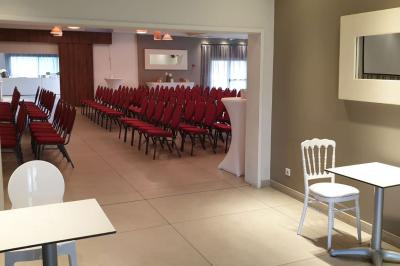 Salle aménagée avec des rangées de chaises rouges alignées, prête pour un événement ou une réunion.