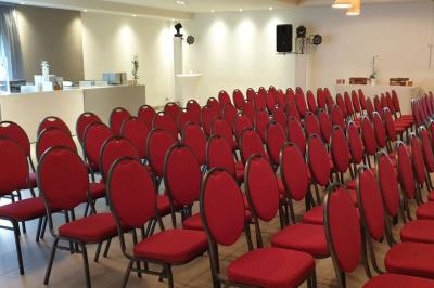 Salle aménagée avec des rangées de chaises rouges alignées, prête pour un événement ou une réunion.