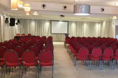 Salle aménagée avec des rangées de chaises rouges alignées, prête pour un événement ou une réunion.