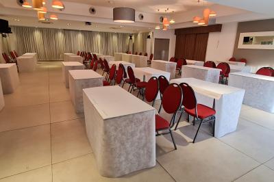 Salle aménagée avec des rangées de chaises rouges alignées, prête pour un événement ou une réunion.