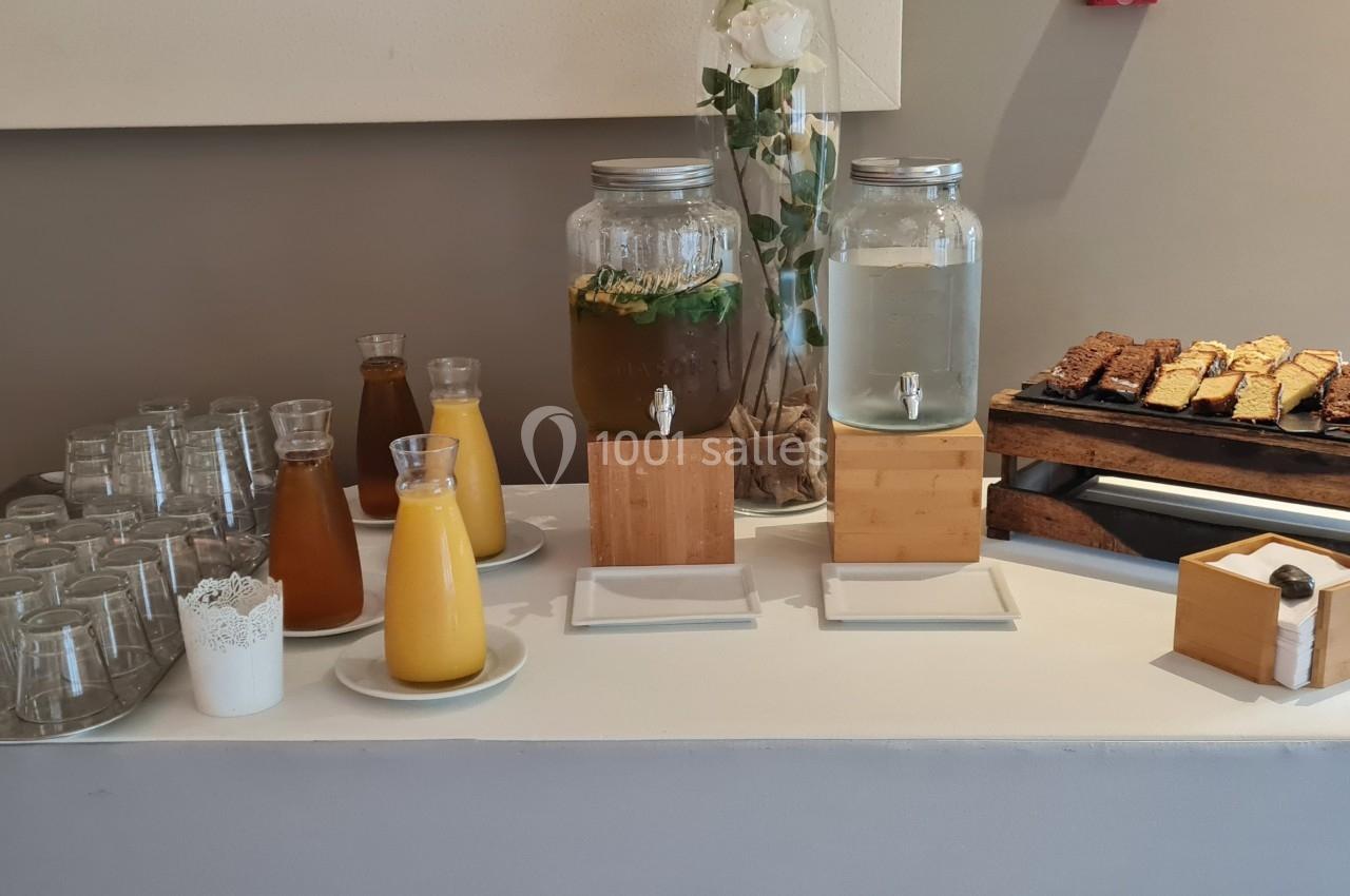 Buffet avec carafes de jus, distributeurs d'eau aromatisée, verres et assortiment de pâtisseries sur un présentoir.