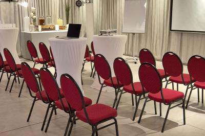 Salle aménagée avec des rangées de chaises rouges alignées, prête pour un événement ou une réunion.