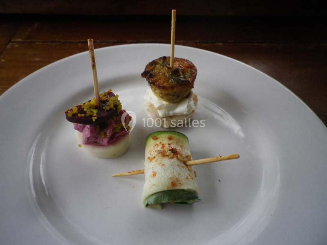 Assortiment de trois amuse-bouches sur une assiette blanche, chacun présenté avec un pique en bois.