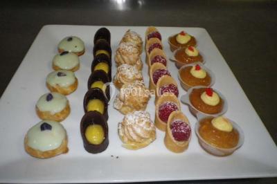 Corbeille garnie de fruits variés et fleurs décoratives, posée sur une table dans un environnement faiblement éclairé.