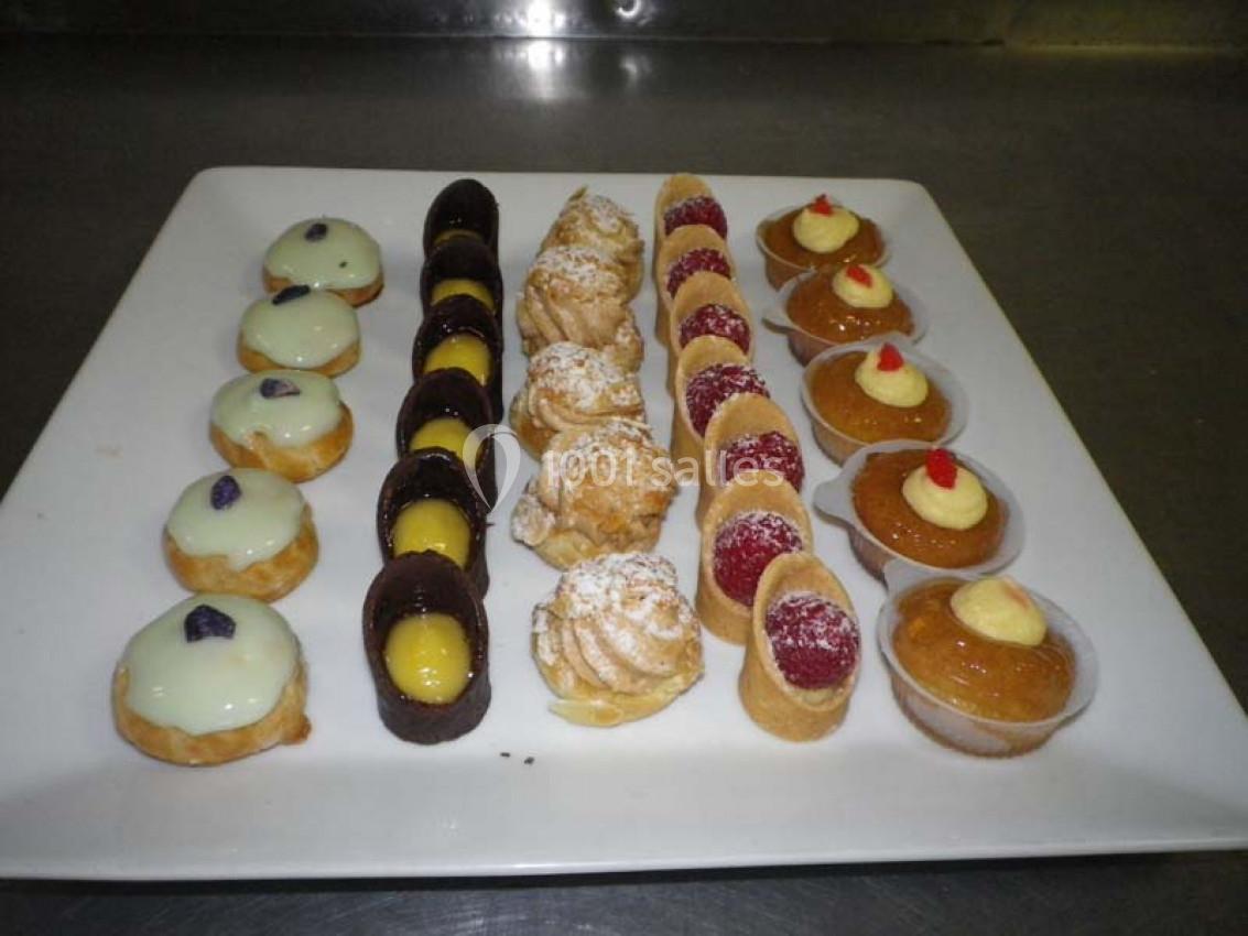Plateau de petits desserts variés, comprenant choux, tartelettes et bouchées au chocolat, disposés en rangées.