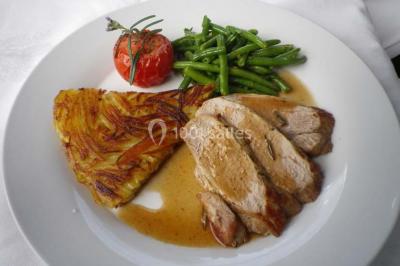 Corbeille garnie de fruits variés et fleurs décoratives, posée sur une table dans un environnement faiblement éclairé.