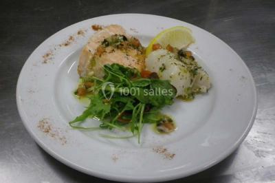 Corbeille garnie de fruits variés et fleurs décoratives, posée sur une table dans un environnement faiblement éclairé.
