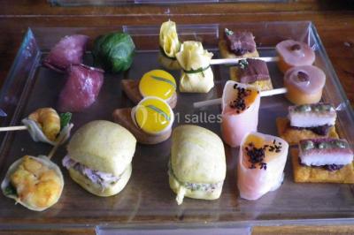 Corbeille garnie de fruits variés et fleurs décoratives, posée sur une table dans un environnement faiblement éclairé.