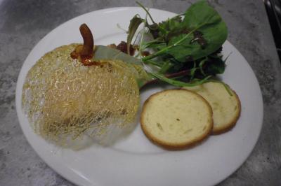 Corbeille garnie de fruits variés et fleurs décoratives, posée sur une table dans un environnement faiblement éclairé.