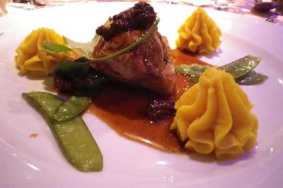 Corbeille garnie de fruits variés et fleurs décoratives, posée sur une table dans un environnement faiblement éclairé.