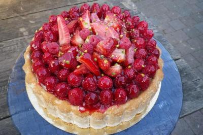 Corbeille garnie de fruits variés et fleurs décoratives, posée sur une table dans un environnement faiblement éclairé.