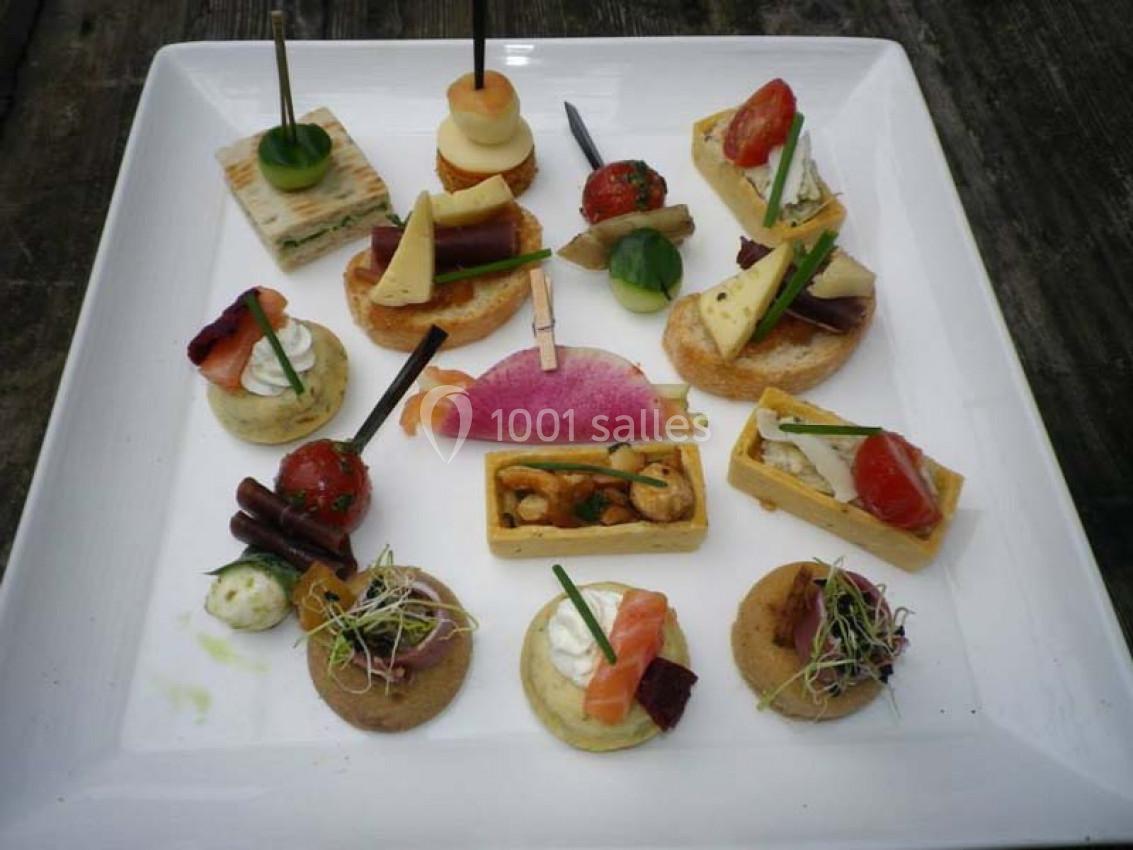 Assortiment de canapés variés disposés sur une assiette blanche, comprenant légumes, saumon et garnitures diverses.