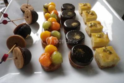 Corbeille garnie de fruits variés et fleurs décoratives, posée sur une table dans un environnement faiblement éclairé.