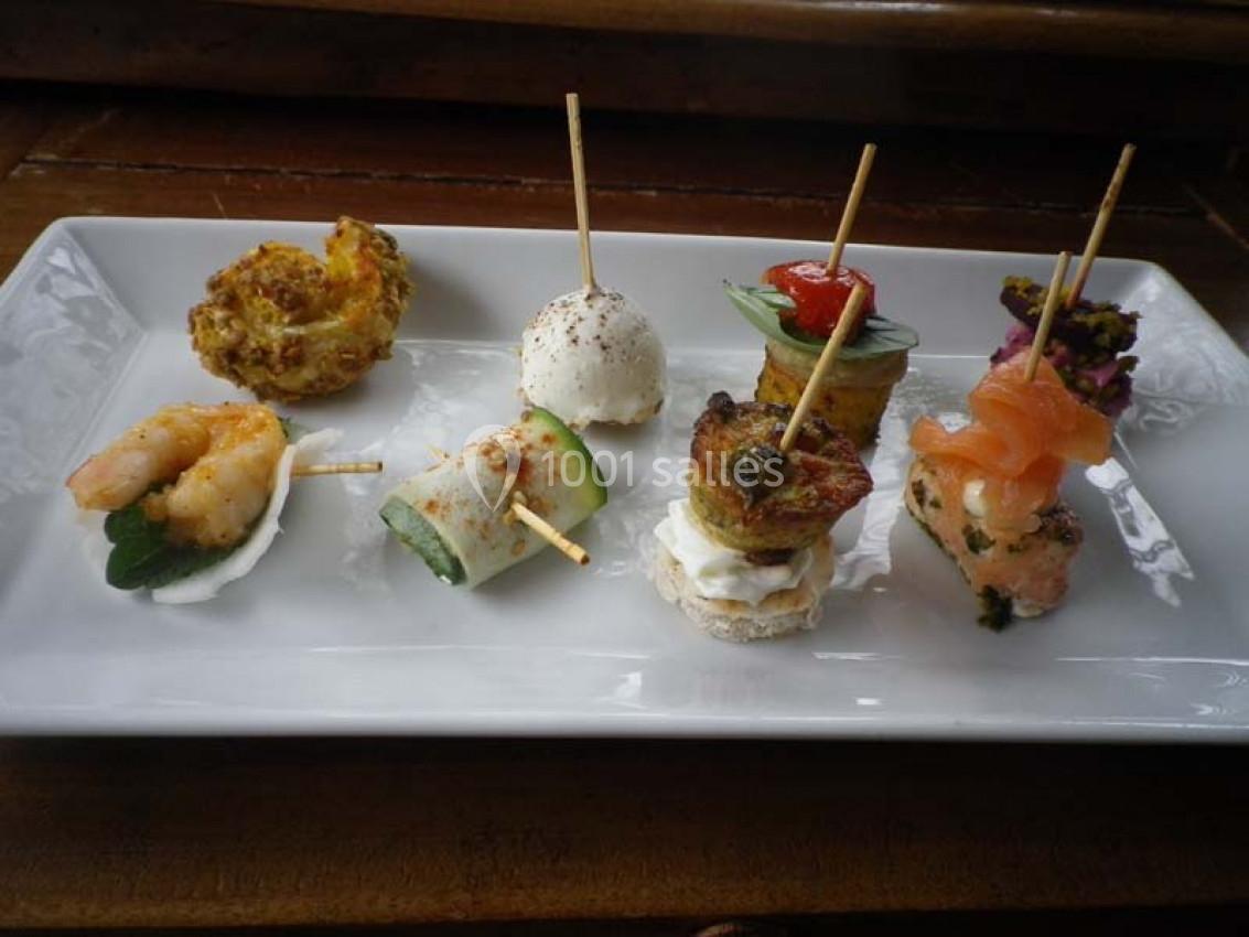 Assortiment de bouchées apéritives variées présentées sur une assiette rectangulaire blanche.