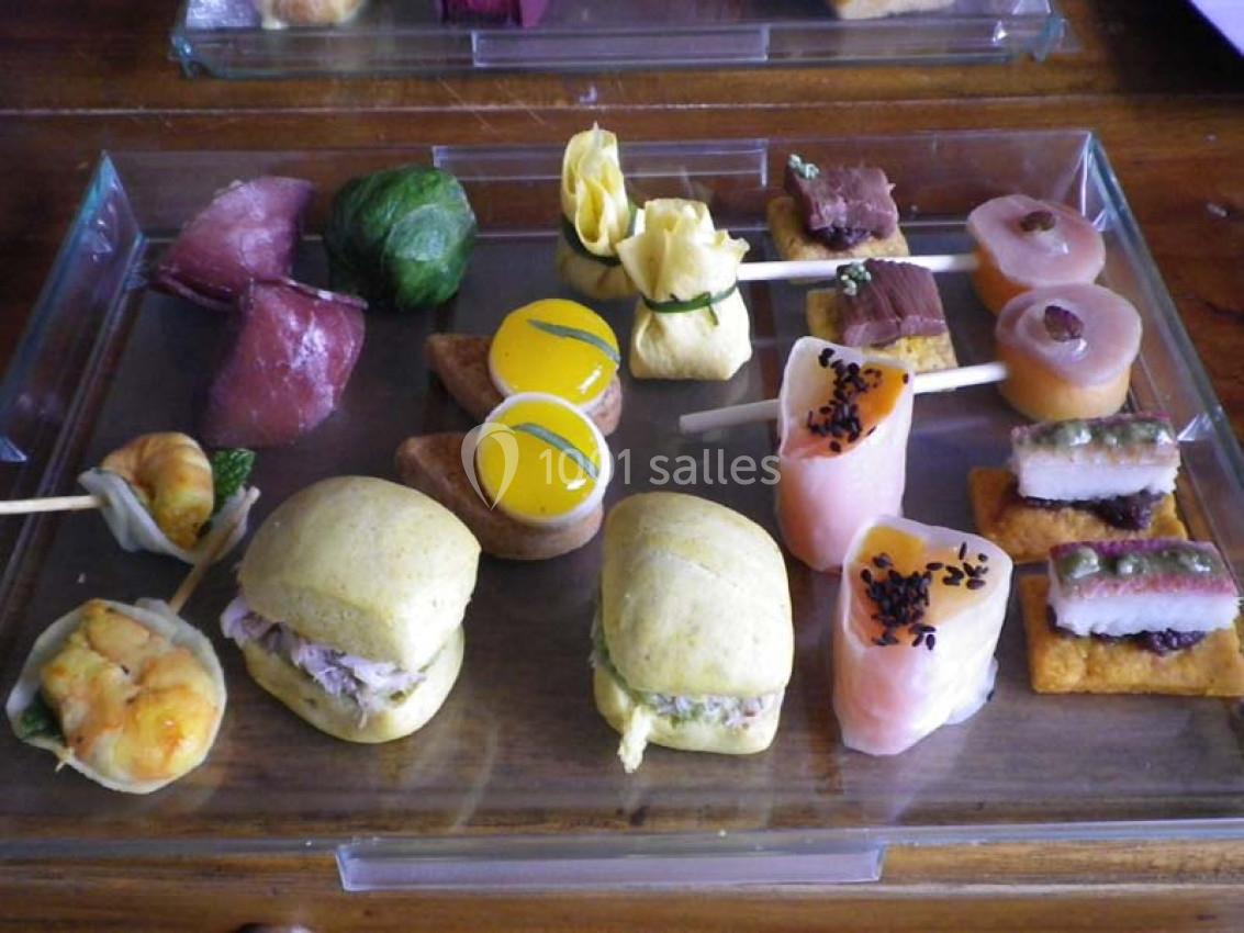 Plateau de bouchées apéritives variées comprenant sushis, mini-sandwichs, brochettes et amuse-bouches colorés.