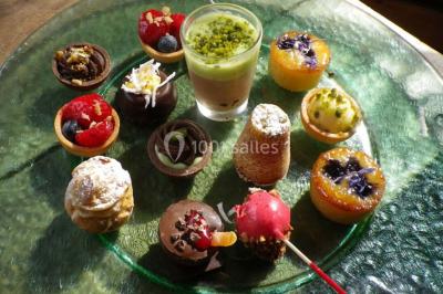 Corbeille garnie de fruits variés et fleurs décoratives, posée sur une table dans un environnement faiblement éclairé.