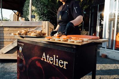 Personne préparant des toasts au saumon fumé sur un stand en extérieur, avec des planches en bois et un décor naturel.