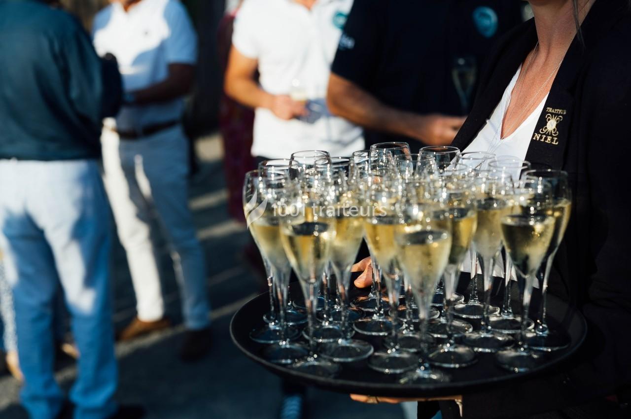 Plateau de verres de champagne tenu par une personne lors d'un événement en extérieur.