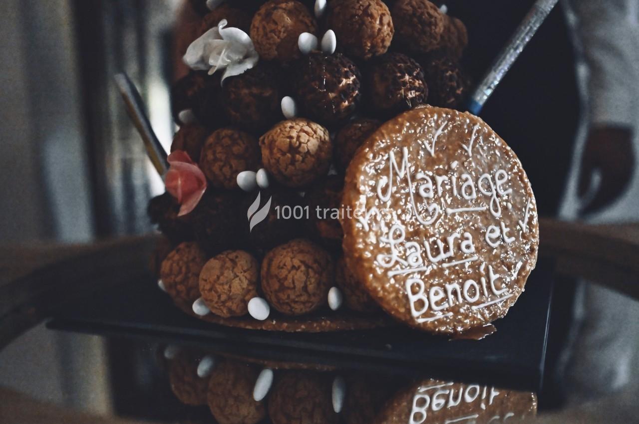 Pièce montée de choux décorée avec une plaque en sucre portant l'inscription ’Mariage Laura et Benoît’.