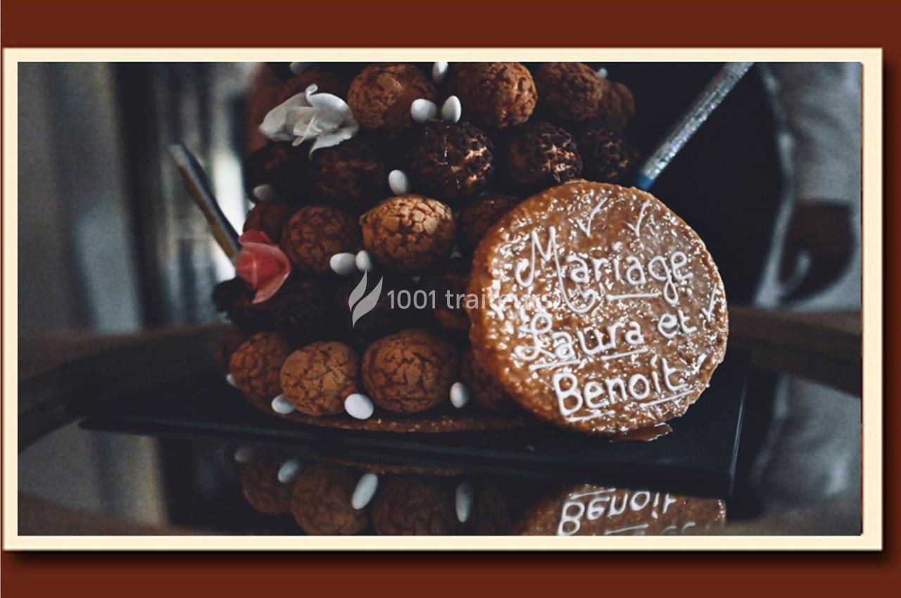 Pièce montée de choux décorée, avec un disque en caramel portant l'inscription ’Mariage Laura et Benoît’.