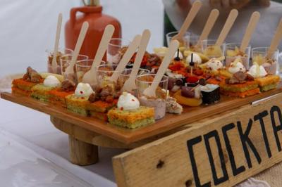Plateau de bouchées apéritives variées présentées sur des supports en bois, avec une pancarte ’Cocktail’.