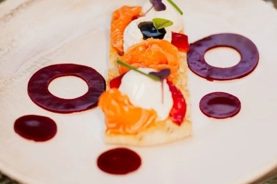 Assiette gastronomique avec filet de viande, purée de carottes, garniture de légumes et sauce décorative.