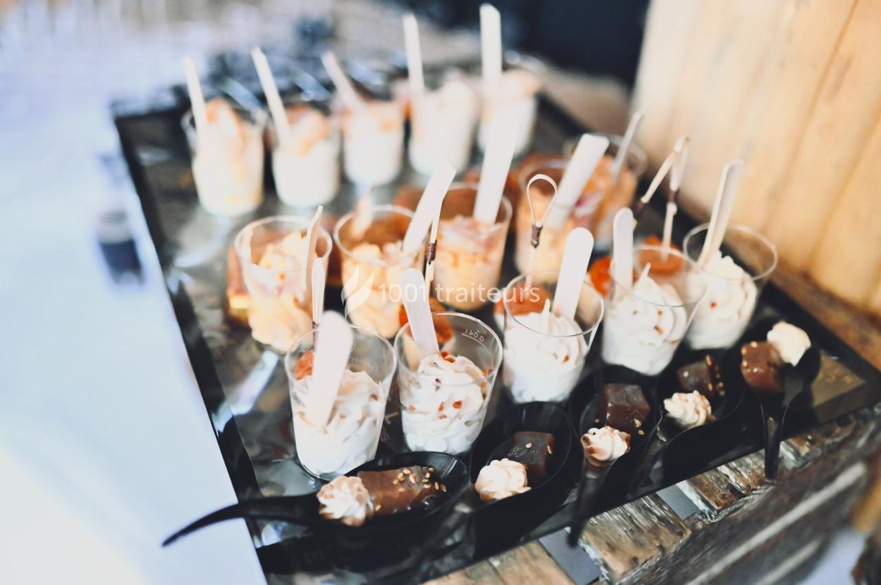 Assortiment de verrines sucrées et cuillères en chocolat disposées sur un plateau noir.