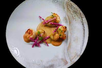 Viande en morceaux grillant sur une plaque chauffante, retournée à l'aide d'une spatule métallique.