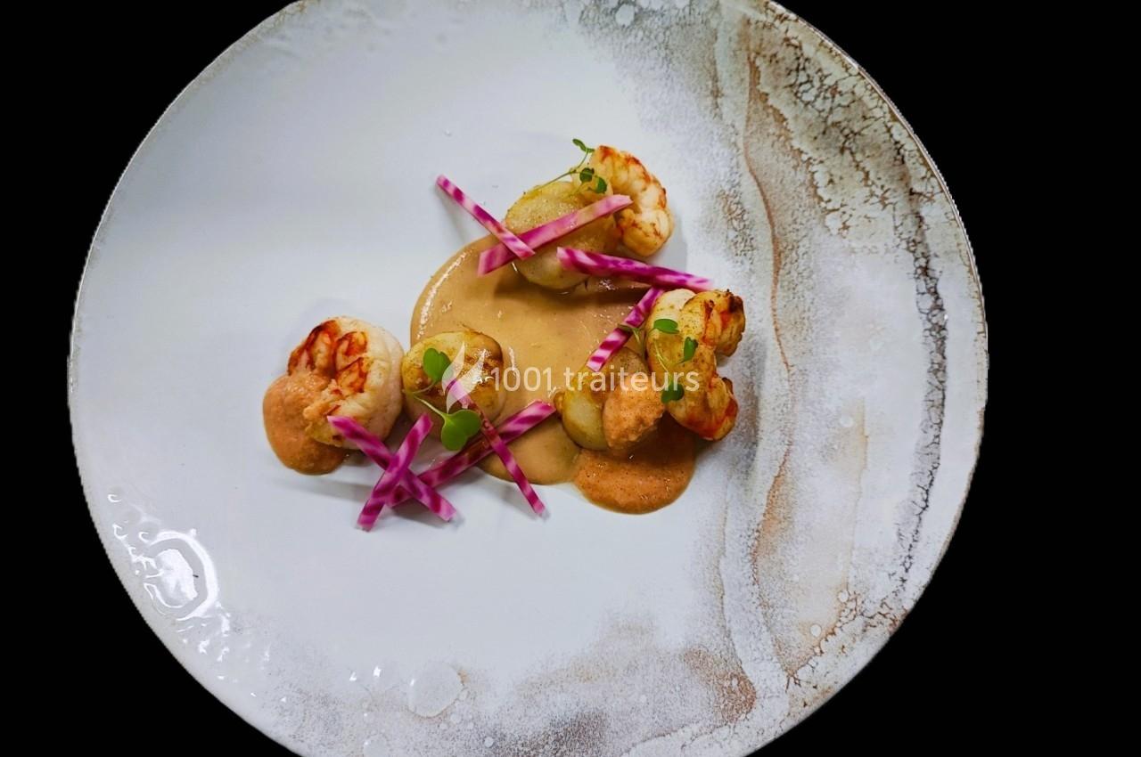 Assiette gastronomique avec crevettes, sauce crémeuse et garniture de légumes colorés sur une présentation soignée.