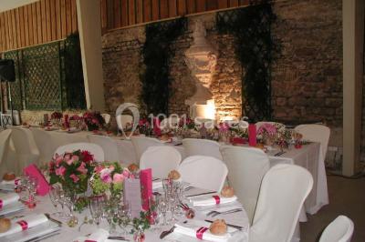 Façade d'un château en briques rouges et blanches avec un toit en ardoise, entouré d'un jardin bien entretenu.