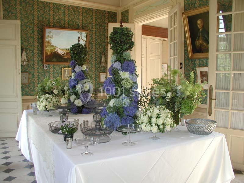 Table décorée avec des compositions florales bleues et blanches dans une pièce élégante au style classique.