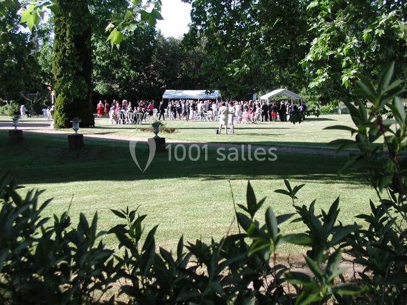 Groupe de personnes rassemblées dans un jardin verdoyant avec des tentes blanches en arrière-plan.