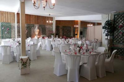 Façade d'un château en briques rouges et blanches avec un toit en ardoise, entouré d'un jardin bien entretenu.