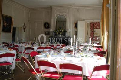 Façade d'un château en briques rouges et blanches avec un toit en ardoise, entouré d'un jardin bien entretenu.
